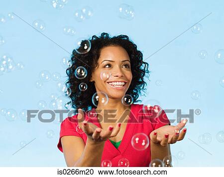 Young woman catching bubbles View Large Photo Image Stock Image - Young woman catching bubbles. Fotosearch