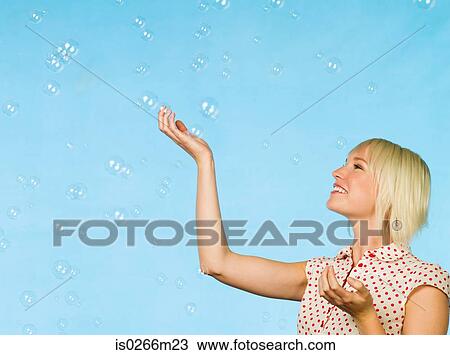 Young woman catching bubbles View Large Photo Image Stock Image - Young woman catching bubbles. Fotosearch