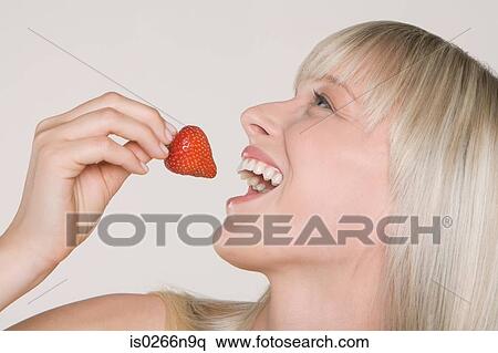 Young woman eating a strawberry View Large Photo Image Stock Photography - Young woman eating a strawberry. Fotosearch