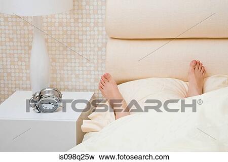 Stock Photo - Feet of person in bed. Fotosearch