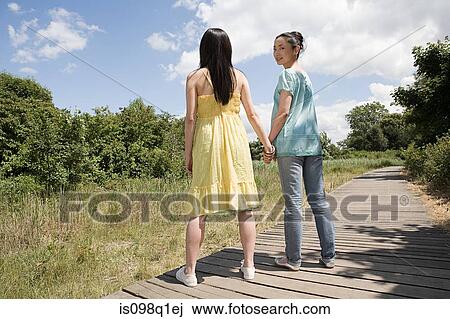 Stock Image - Two women holding hands. Fotosearch