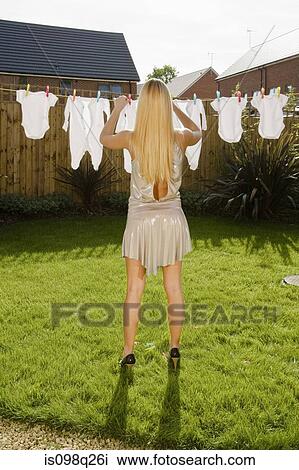 Stock Image - Woman with baby clothes on clothes line. Fotosearch