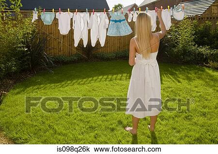 Woman with baby clothes on clothes line View Large Photo Image Stock Image - Woman with baby clothes on clothes line. Fotosearch