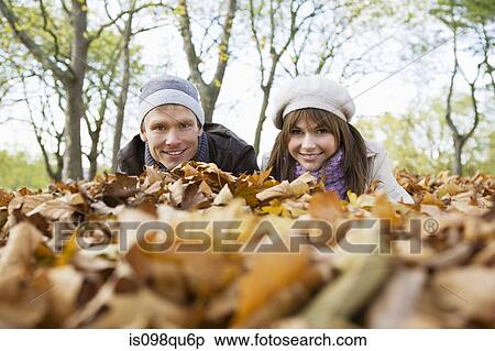 Couple lying on leaves View Large Photo Image Stock Photography - Couple lying on leaves. Fotosearch