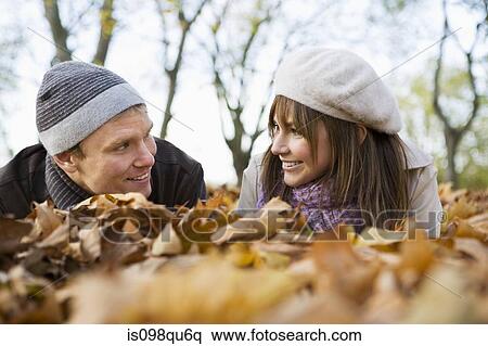 Couple lying on leaves View Large Photo Image Stock Photography - Couple lying on leaves. Fotosearch