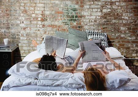 Picture - Couple reading newspapers in bed. Fotosearch