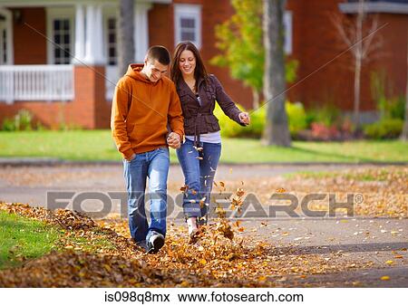 Couple walking and kicking autumn leaves View Large Photo Image Stock Photo - Couple walking and kicking autumn leaves. Fotosearch