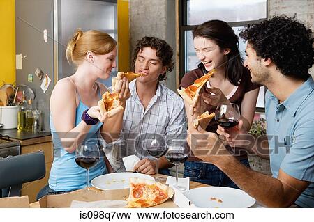 Stock Photo - Friends sharing pizza at home. Fotosearch