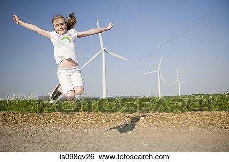 Stock Photograph - Girl jumping near wind farm. Fotosearch