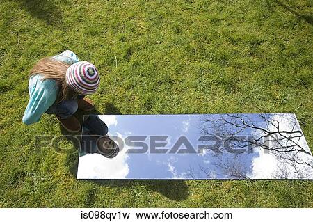 Stock Photo - Girl looking in mirror outdoors. Fotosearch