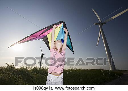 Stock Image - Girl with kite by wind farm. Fotosearch