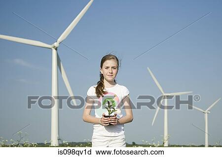 Girl with plant by wind turbines View Large Photo Image Stock Image - Girl with plant by wind turbines. Fotosearch