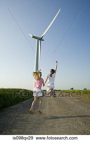 Girls jumping near wind turbine View Large Photo Image Stock Photo - Girls jumping near wind turbine. Fotosearch