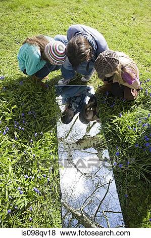 Stock Photo - Girls looking in mirror outdoors. Fotosearch