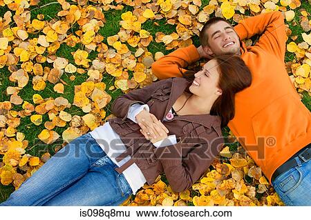Young couple relaxing on the autumn leaves View Large Photo Image Stock Photograph - Young couple relaxing on the autumn leaves. Fotosearch