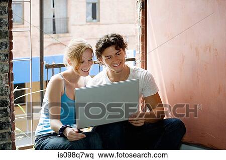 Young couple using a laptop computer View Large Photo Image Stock Photography - Young couple using a laptop computer. Fotosearch