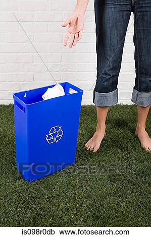 Stock Image - A woman throwing paper into a recycling bin. Fotosearch