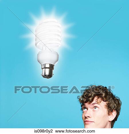 A young man looking at an energy saving lightbulb View Large Photo Image Stock Image - A young man looking at an energy saving lightbulb. Fotosearch