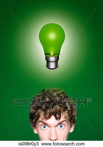 Stock Image - A young man with a green lightbulb over his head. Fotosearch