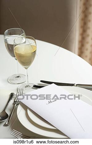 Glass of white wine and a menu on a table View Large Photo Image Stock Photograph - Glass of white wine and a menu on a table. Fotosearch
