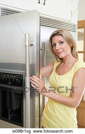 Portrait of a young woman opening a fridge door View Large Photo Image Stock Image - Portrait of a young woman opening a fridge door. Fotosearch