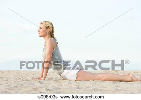 Stock Photograph - Woman doing yoga on beach. Fotosearch