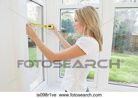 Young woman measuring a window View Large Photo Image Stock Image - Young woman measuring a window. Fotosearch