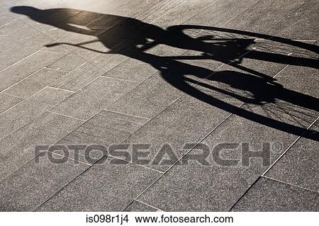 Picture - Shadow of a person riding a bike. Fotosearch