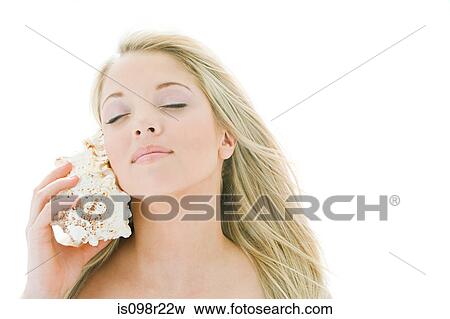 Woman holding shell to ear View Large Photo Image Stock Photo - Woman holding shell to ear. Fotosearch