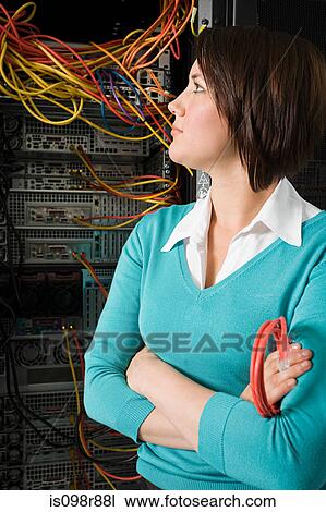 Stock Image - Female computer technician looking at a server. Fotosearch