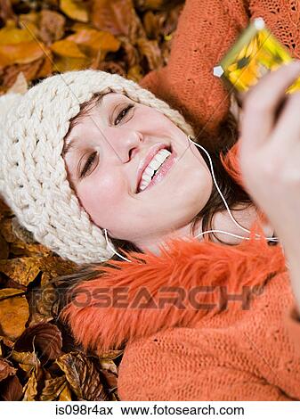 Woman listening to music on autumn leaves View Large Photo Image Stock Photo - Woman listening to music on autumn leaves. Fotosearch
