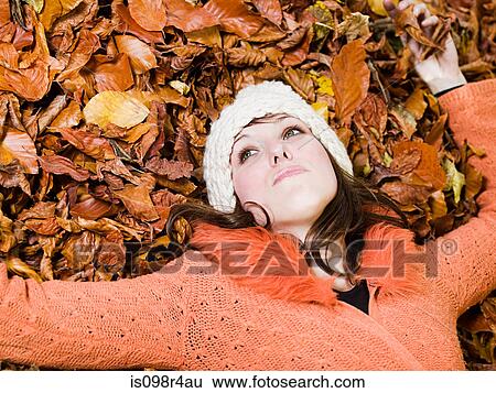 Stock Photograph - Woman lying on autumn leaves. Fotosearch