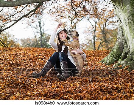 Stock Image - Woman playing with dog in a forest. Fotosearch
