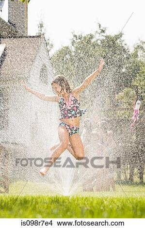 Girl jumping in sprinkler View Large Photo Image Picture - Girl jumping in sprinkler. Fotosearch