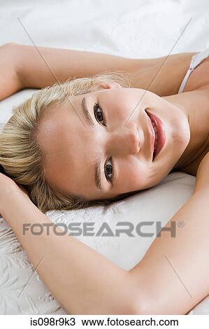 Stock Image - Young woman lying on bed. Fotosearch