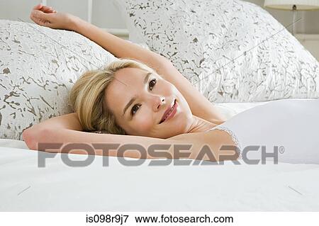 Young woman lying on bed View Large Photo Image Stock Photo - Young woman lying on bed. Fotosearch