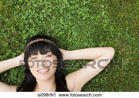 Young woman lying on grass View Large Photo Image Stock Image - Young woman lying on grass. Fotosearch