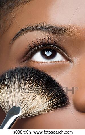 Stock Image - Woman with makeup brush near eye. Fotosearch