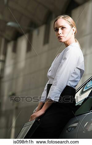 Stock Image - Businesswoman leaning on a car. Fotosearch
