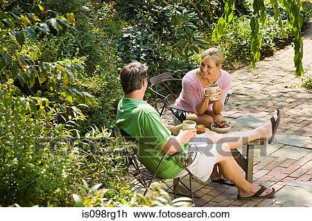 Stock Image - Couple having drink in garden. Fotosearch