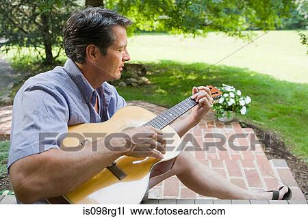Stock Image - Man playing guitar outdoors. Fotosearch