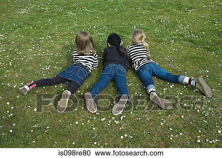 Three girls lying on grass View Large Photo Image Stock Image - Three girls lying on grass. Fotosearch