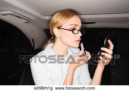 Woman applying lipstick in car View Large Photo Image Stock Image - Woman applying lipstick in car. Fotosearch