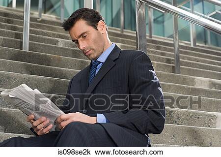 A businessman sitting on steps with a newspaper View Large Photo Image Stock Image - A businessman sitting on steps with a newspaper. Fotosearch