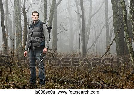 A male hiker standing in a misty forest opening View Large Photo Image Stock Photograph - A male hiker standing in a misty forest opening. Fotosearch