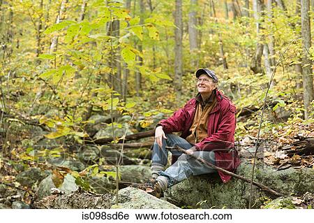 A man sitting on a rock in woodland View Large Photo Image Stock Image - A man sitting on a rock in woodland. Fotosearch