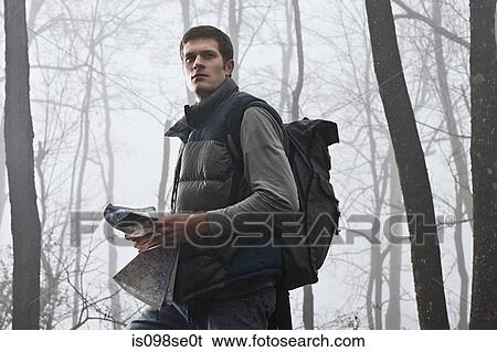 A young male hiker holding a map in a misty forest View Large Photo Image Stock Photograph - A young male hiker holding a map in a misty forest. Fotosearch