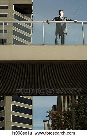 Stock Photograph - Looking up to a businessman on a bridge. Fotosearch