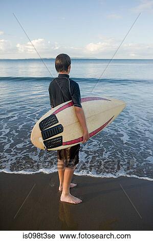 Auckland, young man with surf board on Muriwai Beach View Large Photo Image Stock Image - Auckland, young man with surf board on Muriwai Beach. Fotosearch
