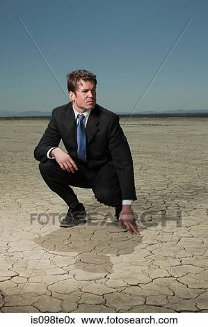 Businessman crouching in desert landscape View Large Photo Image Stock Photo - Businessman crouching in desert landscape. Fotosearch